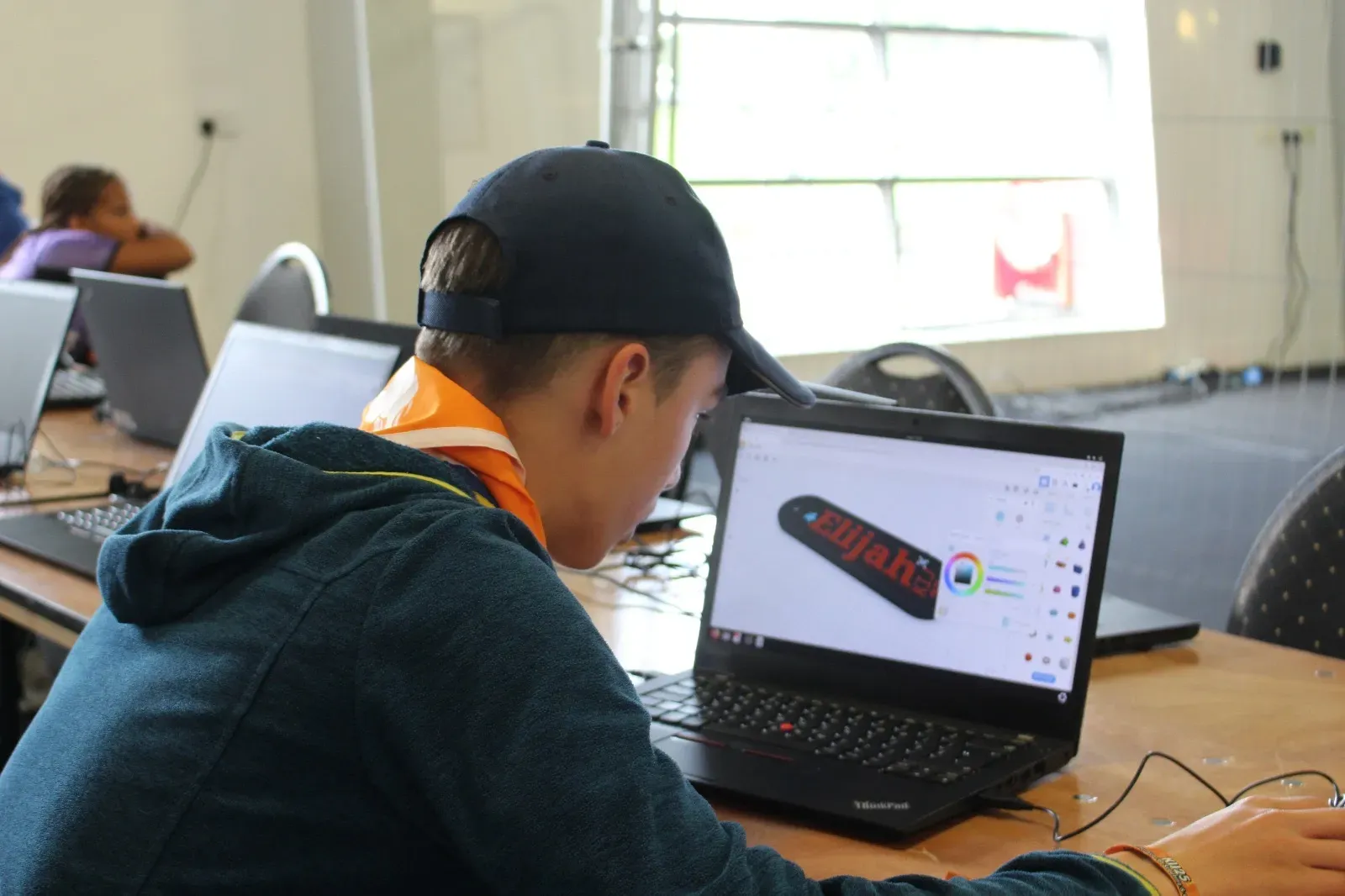 Young people making freshly 3D printed name tags at a workshop.